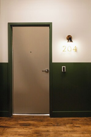 A closed door with a number 204 sign above it, a wall-mounted light, and a doorbell. - Toledo Loft | Walk to Ballpark | Suite 204 (Toledo)