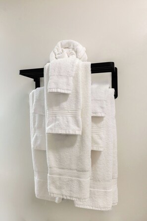 A white towel folded and hung on a black towel rack. - Toledo Loft | Walk to Ballpark | Suite 204 (Toledo)
