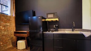 A compact kitchen with a refrigerator, microwave, sink, and a small wooden table. - Toledo Loft | Walk to Ballpark | Suite 204 (Toledo)
