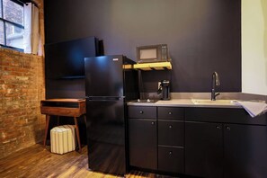A compact kitchen with a refrigerator, microwave, sink, and a small wooden table. - Toledo Loft | Walk to Ballpark | Suite 204 (Toledo)