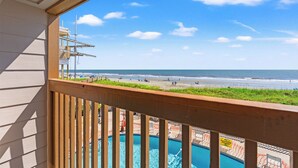 Un balcon avec vue sur une plage et une piscine.