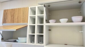 A kitchen with white cabinets, a wooden countertop, and a hanging rack. - 2 Min da Praia - 2Q - Vaga de Garagem (Santos)