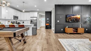 Una cucina moderna con mobili bianchi, un tavolo da pranzo in legno e un piano di lavoro nero.