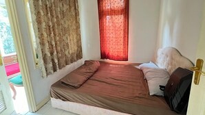 Un dormitorio con cama, cortinas y una puerta.