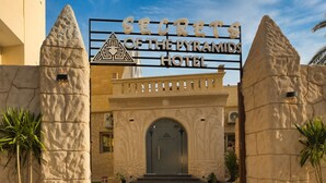 La entrada al Hotel Secret's of the Pyramids, con un cartel grande sobre la puerta, pilares de piedra y diseños decorativos en la pared.
