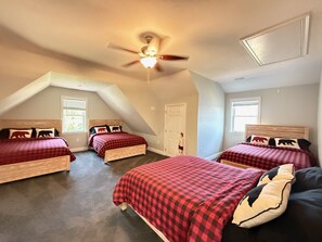 A bedroom with three beds, a ceiling fan, and a sloped ceiling. - Hilltop Haven on Lake Winnisquam (Sanbornton)