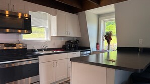 A modern kitchen with white cabinets, stainless steel appliances, and a large island. - Lakeside A-Frame- Cozy Beach Access Retreat (Sanbornton)