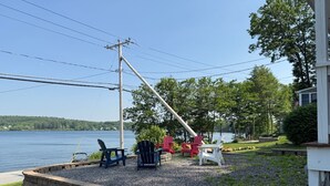 A lakeside patio with Adirondack chairs, a stone retaining wall, and a view of the lake. - Lakeside A-Frame- Cozy Beach Access Retreat (Sanbornton)