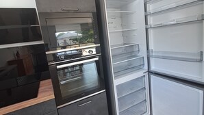 Une cuisine moderne dotée d’un four encastré, d’un réfrigérateur à multiples compartiments et d’un plancher en bois.