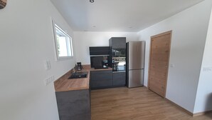 Une cuisine moderne avec un plan de travail en bois, des meubles de couleur noire et un four encastré.