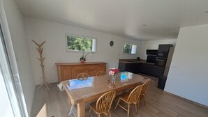 Un coin repas avec une table et des chaises en bois, un vase de fleurs et une vue sur la cuisine.
