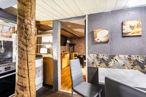Una cocina moderna con un pilar de madera, horno empotrado y comedor con salpicadero de mármol.