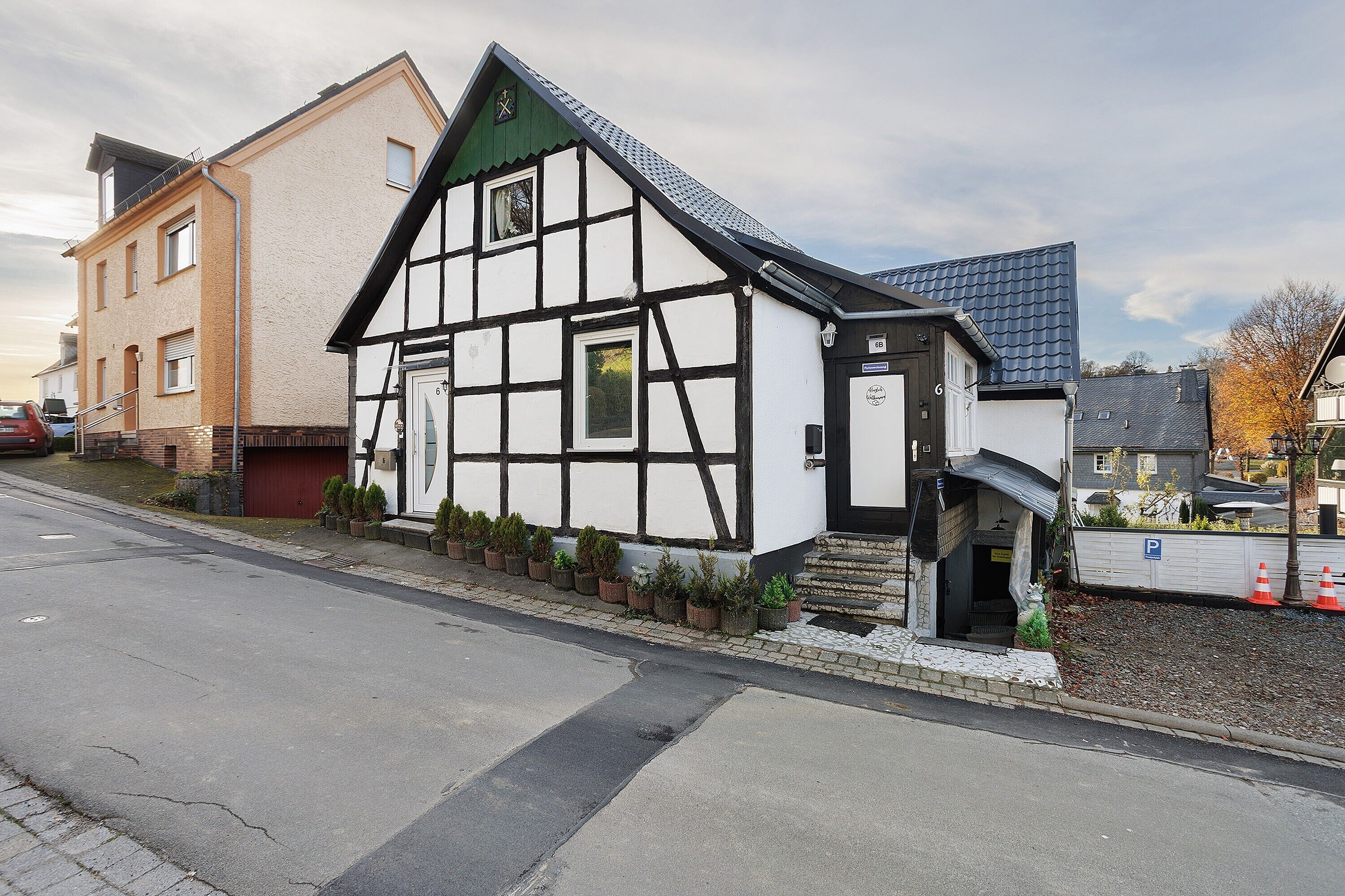 A traditional half-timbered building with a steeply pitched roof, a visible entrance, and a small porch area.