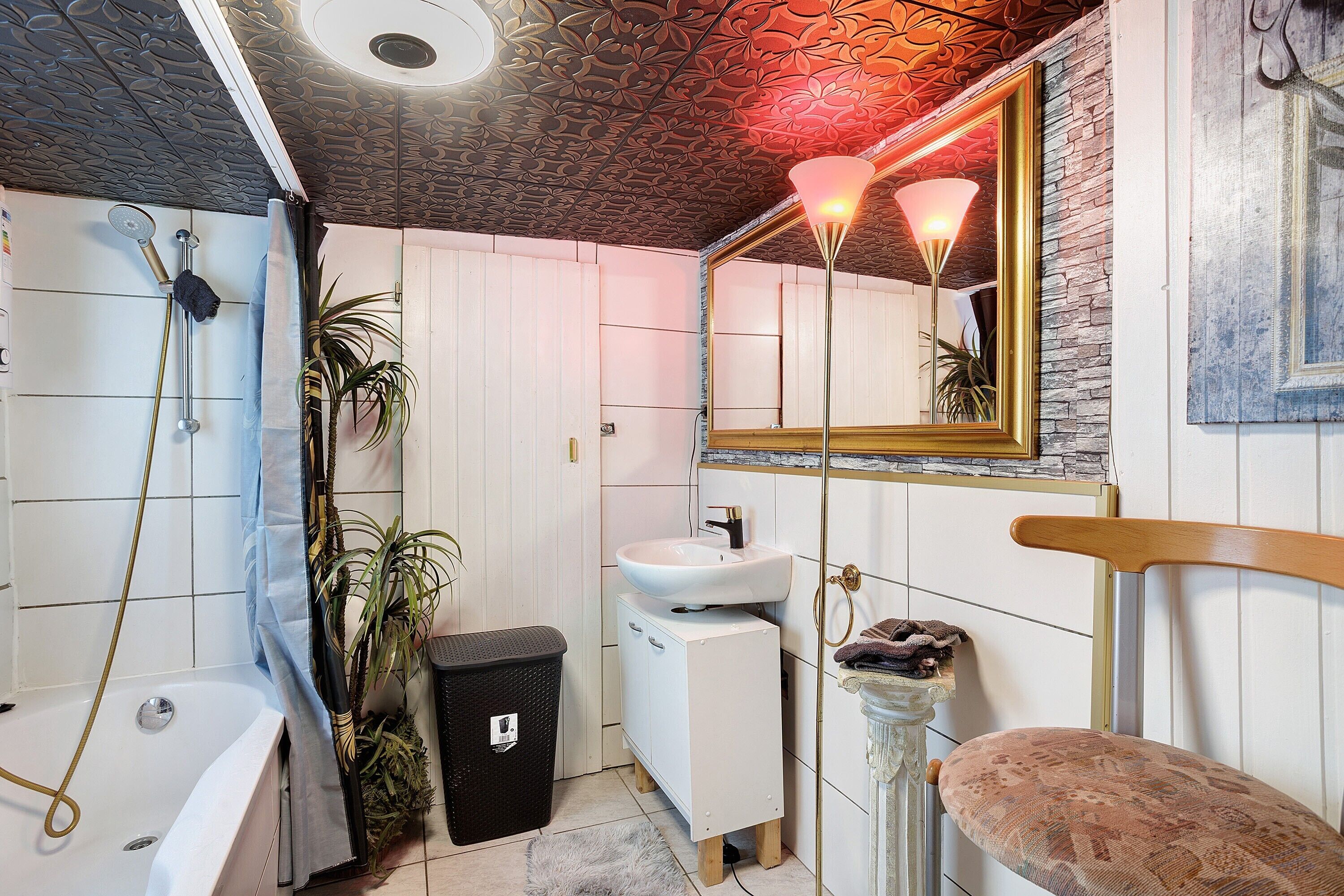 A bathroom with a bathtub, shower, sink, and a mirror with a wooden frame.
