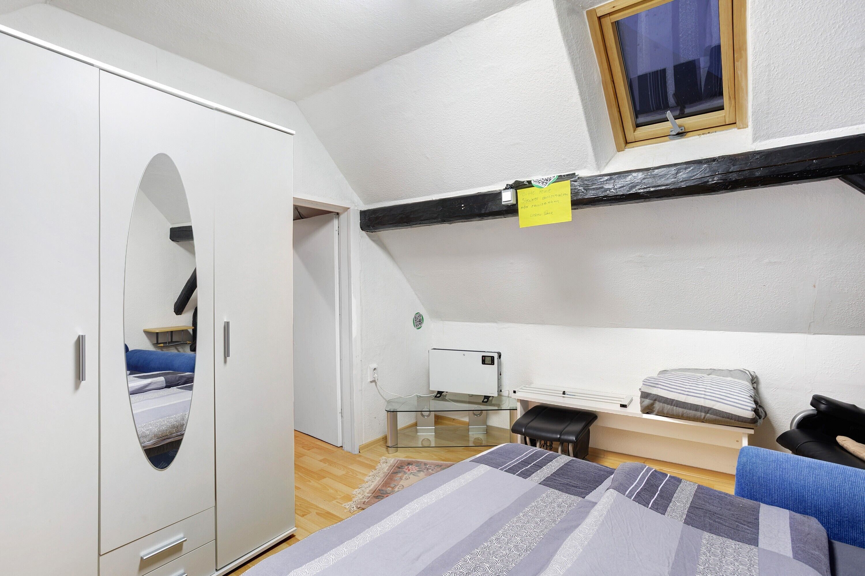 A bedroom with a bunk bed, a wardrobe, a desk, and a window.