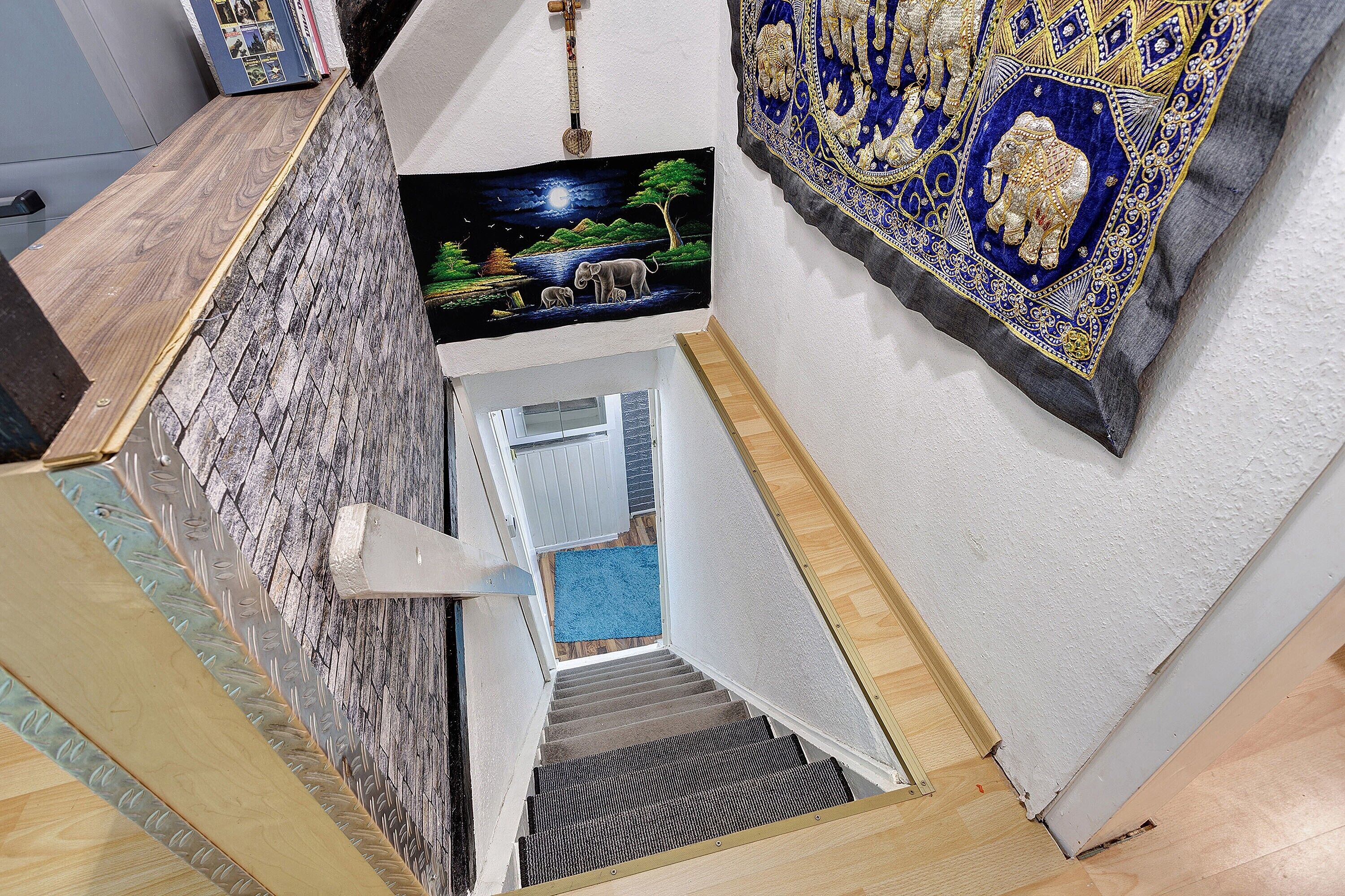 Een trap met een structuurwand, een lijst met een afbeelding en een decoratief textiel.