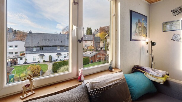 A room with a large window, a bed, a small table, and a wall-mounted lamp. - Apartment 'Happy' with Mountain View, Private Garden and Wi-Fi (Olsberg)