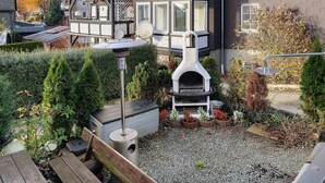 A residential area with a two-story house, a barbecue grill, and a wooden deck. - Apartment 'Happy' with Mountain View, Private Garden and Wi-Fi (Olsberg)