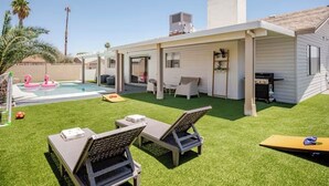 A backyard with a pool, artificial grass, lounge chairs, and a barbecue area. - Retro Modern Oasis Pool Golf (Las Vegas)