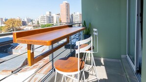A balcony with a wooden table and two chairs, a potted plant, and a city view. - Hornera Caffe - Terminal, Bioceres, IUNIR (Rosario)