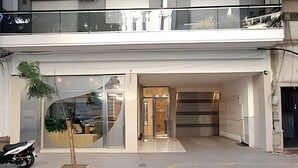 Un edificio moderno con fachada de vidrio, entrada visible y una motocicleta estacionada afuera.