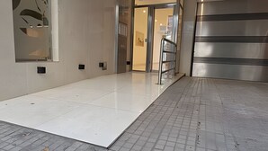 Un vestíbulo amplio con piso de baldosas, puerta de cristal y refrigerador de acero inoxidable.