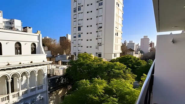 Un edificio moderno de gran altura, rodeado de vegetación y otros edificios.