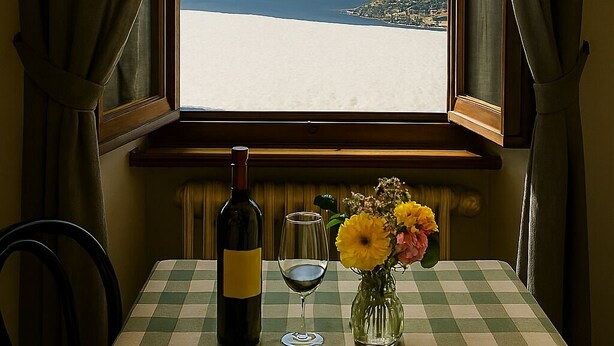 A table set with a bottle of wine, a glass, a plate, and cutlery, with a view of a lake and mountains through a window. - Baita Cao Como Lake (Brunate)