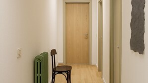 A hallway with a wooden floor, a radiator, a chair, and a door at the end. - Baita Cao Como Lake (Brunate)