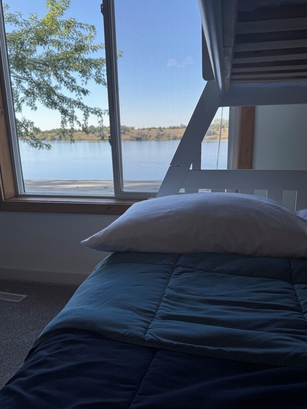 Un dormitorio con cama, ventana y vista al lago.