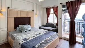 A bedroom with a bed, bedside tables, a ceiling light fixture, a window with curtains, and an air conditioning unit.