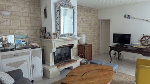 Una sala de estar con chimenea, televisor y un sillón amarillo.