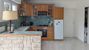 Una cocina compacta con armarios de madera, estufa integrada y un refrigerador.