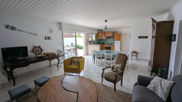 Una sala de estar con una mesa de centro de madera, un sofá, un sillón amarillo y un televisor sobre un mueble de madera.