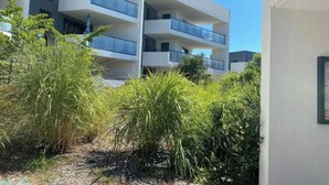 A modern multi-story building with balconies, surrounded by lush greenery.