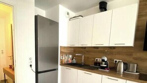 A modern kitchen with white cabinets, a stainless steel refrigerator, and a wooden countertop.
