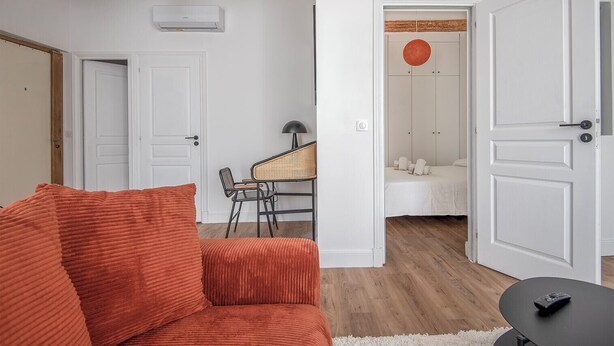 A room with a red sofa, a table with chairs, a bed with a white headboard, and a door leading to another room. - Apartment in the heart of Marseille, well located (Marseille)