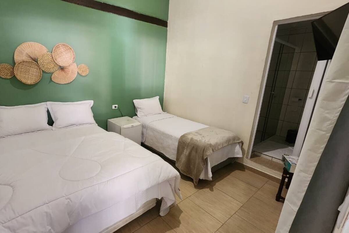Habitación con dos camas, una pared verde de acento y una mesita con una cesta.