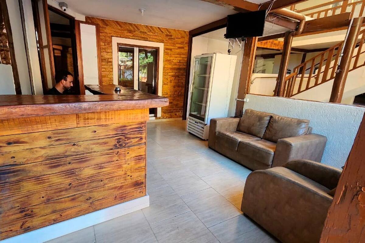 Un mostrador de recepción de madera en un área de estar moderna, con un sofá y una escalera.