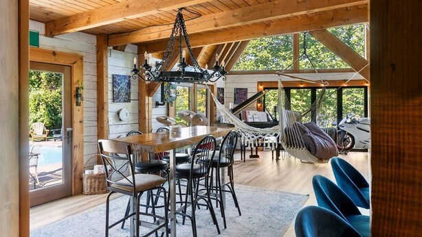 A wooden interior with a dining area, a hammock, and a view of the outdoors.
