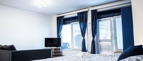Une chambre moderne avec un grand lit, un téléviseur à écran plat, un canapé et une fenêtre avec des rideaux.
