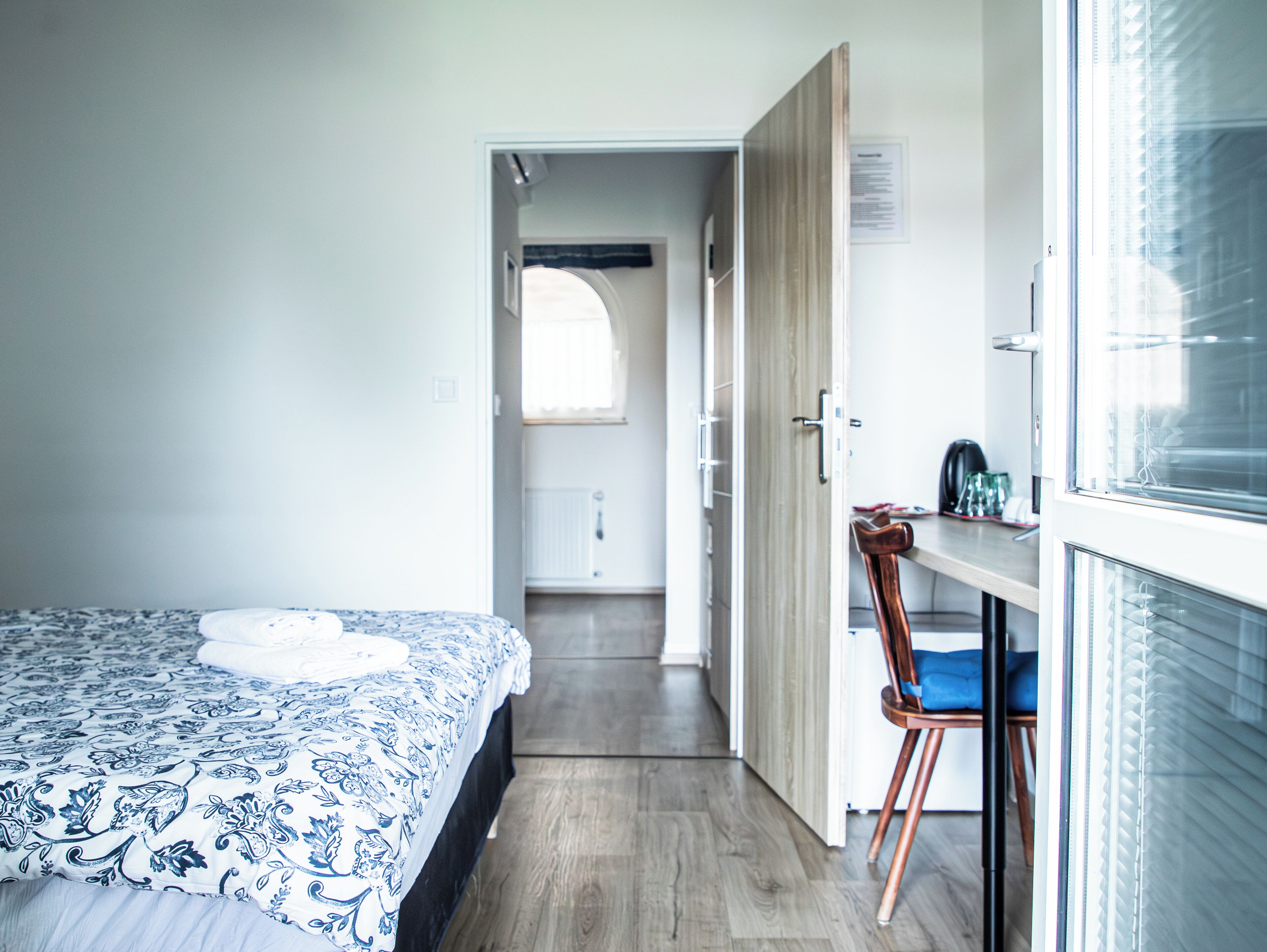Un dormitorio con cama, una silla, un escritorio y una ventana.
