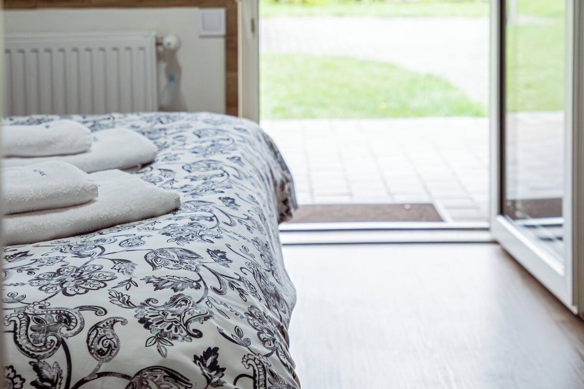 Una camera da letto con un letto, un termosifone e vista sull'esterno attraverso una porta.