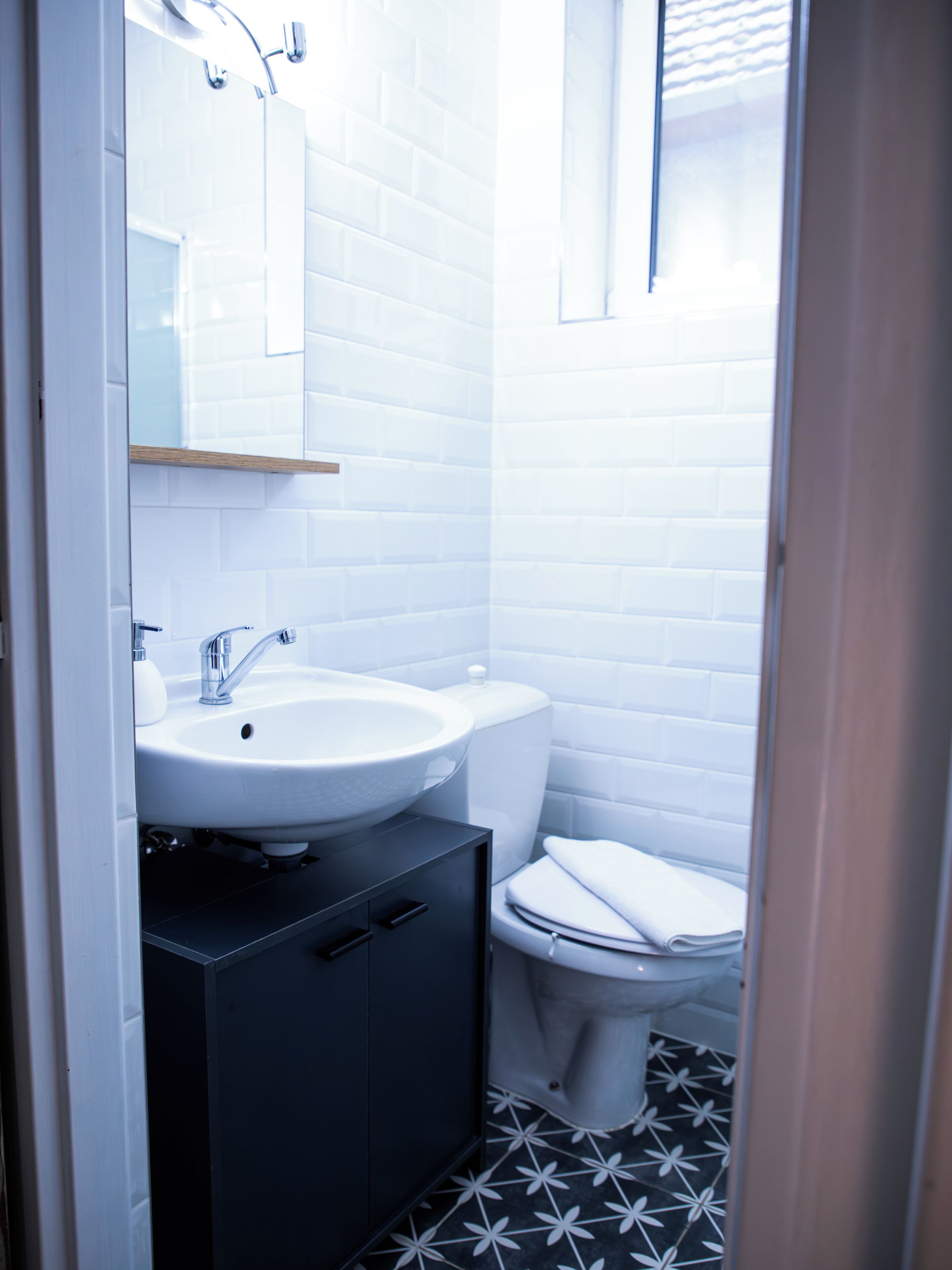Une petite salle de bain avec un lavabo blanc, des toilettes et un meuble de couleur sombre.