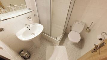 Une salle de bain équipée d’un lavabo, de toilettes, d’une douche et d’une poubelle.