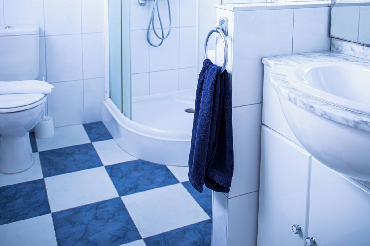 Un bagno moderno con cabina doccia a semicircolo, un water bianco e un pavimento a scacchi.