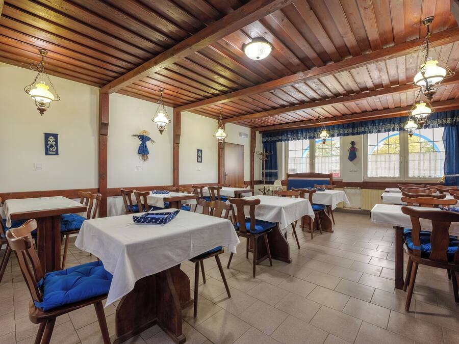 Un restaurante con vigas de madera, manteles blancos y sillas azules acolchadas.