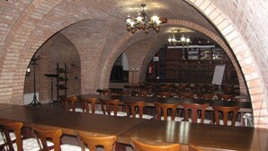 A restaurant with brick arches, wooden tables, and chairs. - Penzion Posada Podivín (Podivin)