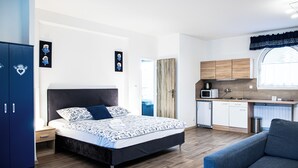 A modern bedroom with a large bed, a small kitchenette, and a blue wardrobe. - Penzion Posada Podivín (Podivin)
