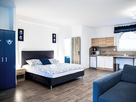 Un dormitorio moderno con una cama grande, un pequeño rincón americano y un armario azul.